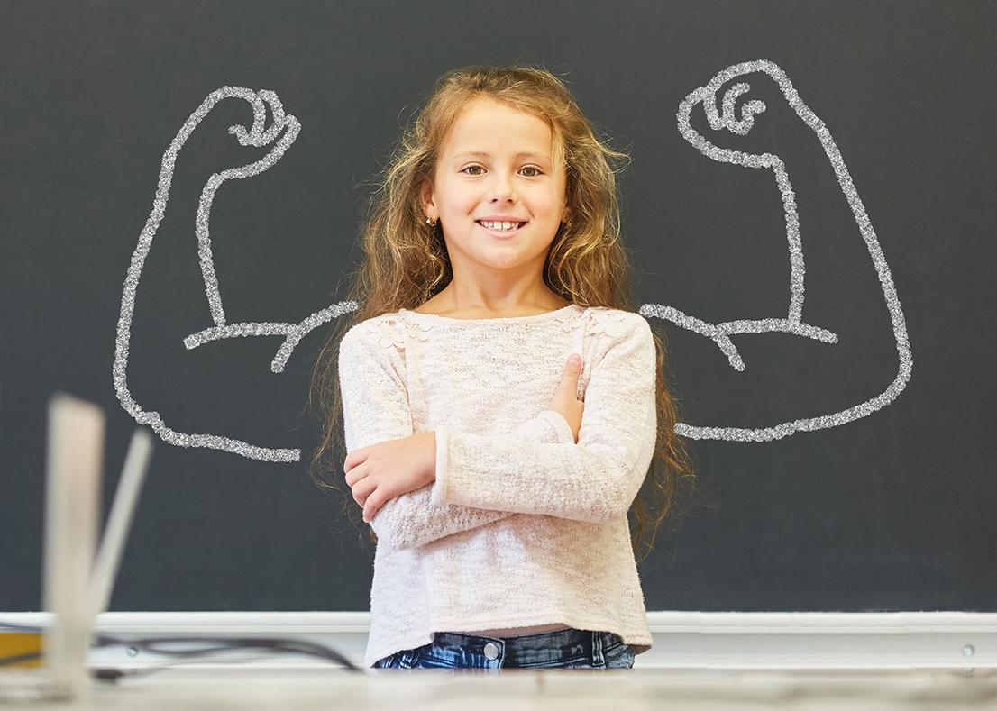 L&auml;chelndes M&auml;dchen in der Schule steht vor einer Tafel mit Muskeln aus Kreide