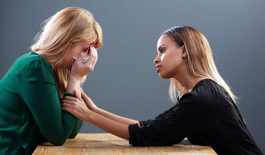 Eine weinenden Frau wird von einer anderen Frau getröstet.