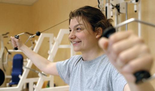 Eine junge Frau macht Sportübungen an einem Sportgerät.