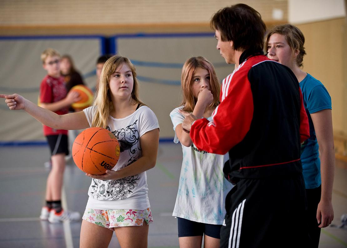 Eine Sportlehrerin unterh&auml;lt sich mit drei Sch&uuml;lerinnen.