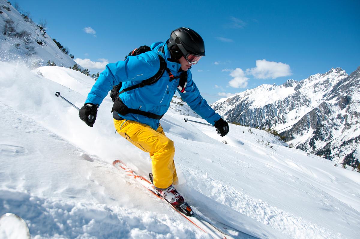 Großansicht: Eine Person in Winterkleidung fährt mit Skiern einen Hang runter.