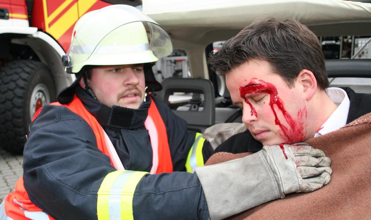 Öffnet eine Lightbox: Der Mann mit der blutenden Verletzung über dem Auge wird von einem Feuerwehrmann erstversorgt.