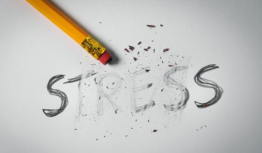 Das Wort „Stress“ wurde mit Bleistift auf ein Blatt Papier geschrieben, dann teilweise ausradiert. Ein Bleistift mit einem Radiergummi am Ende liegt auf dem Papier. Beim Radiervorgang entstandener Dreck wurde nicht entfernt.