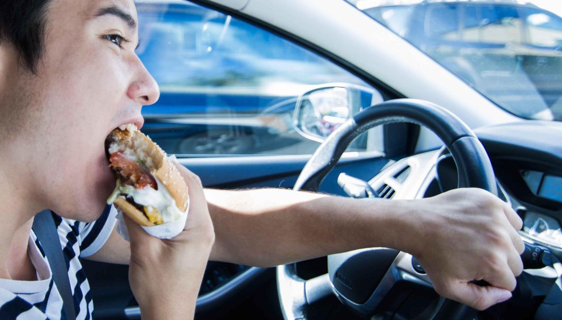 Großansicht: Der Fahrer isst beim Fahren.