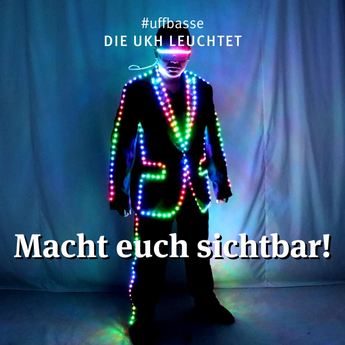 Öffnet eine Lightbox: Mann mit Anzug und Lichterkette vor blauem Hintergrund. Text: Macht Euch sichtbar!