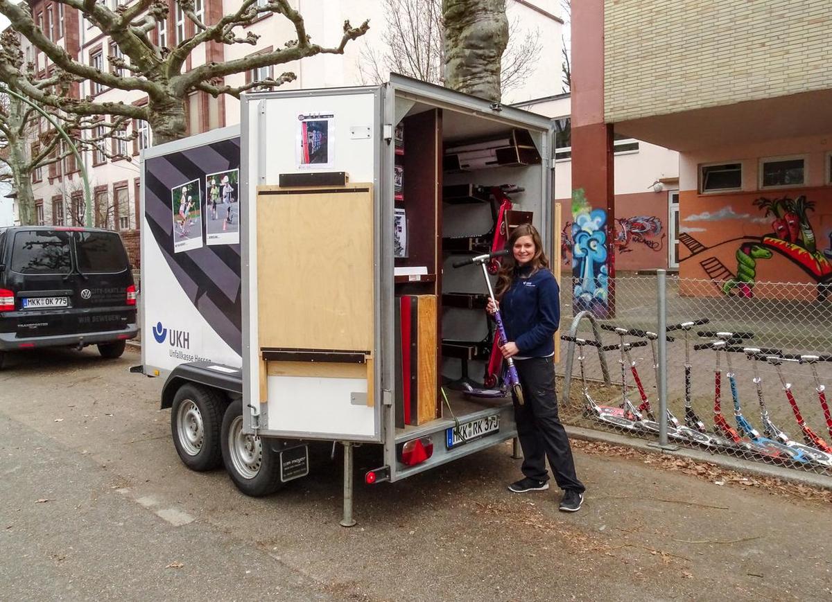 Öffnet eine Lightbox: Eine Frau steht vor dem UKH RollerKIDS-Mobil.