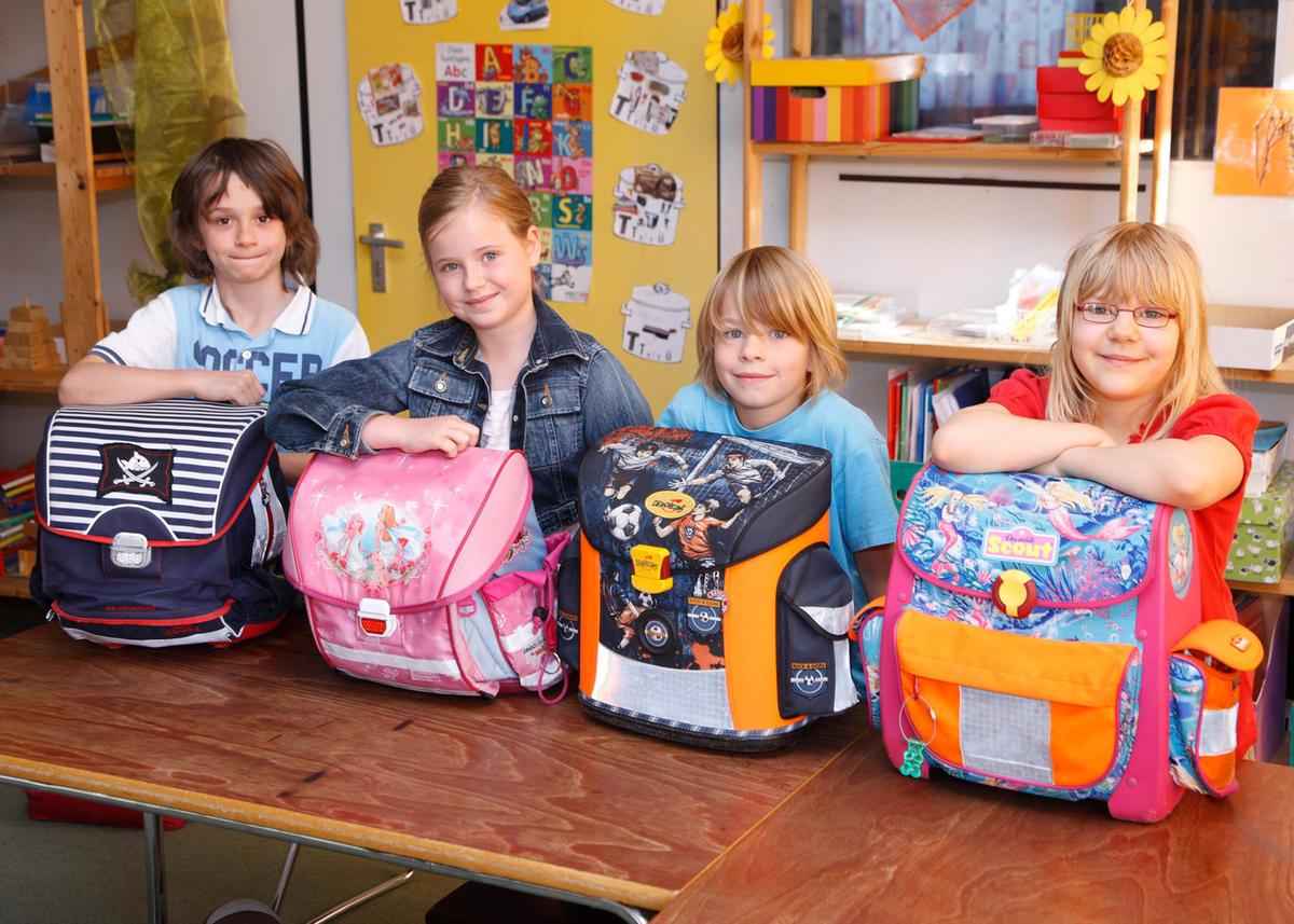 Öffnet eine Lightbox: Vier Schulkinder posieren in einem Klassenzimmer mit ihren Schulranzen.